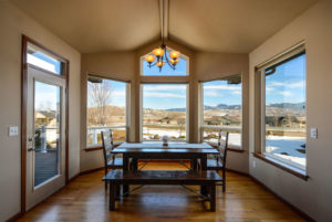 A dining room with a table and chairs, and a view of the mountains.