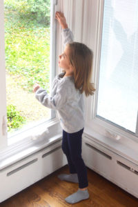 A little girl standing in front of a window.