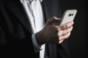 A man in a suit holding his cell phone.