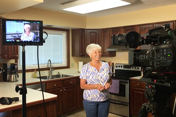 A woman standing in the kitchen with a camera.