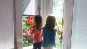 Two little girls standing in front of a window.